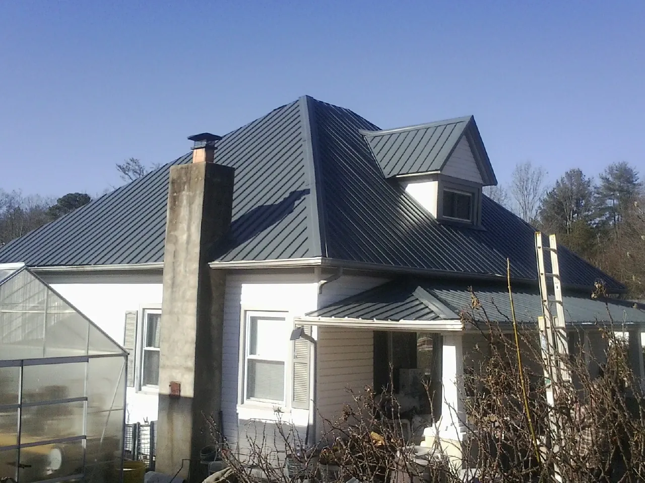 Dark blue standing seam metal roof on a white farmhouse with dormer — Slate & Tile Roof Repair by Roofing Brothers in Dorchester Center