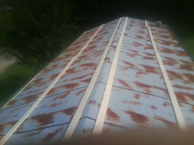 Rusted metal roof panels with new wood purlins before replacement — Storm Damage Roof Repair in Dorchester Center by Roofing Brothers