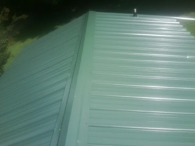 New green metal panels meeting at the ridge of a roof — Flat Roof Repair work by our crew in Dorchester Center