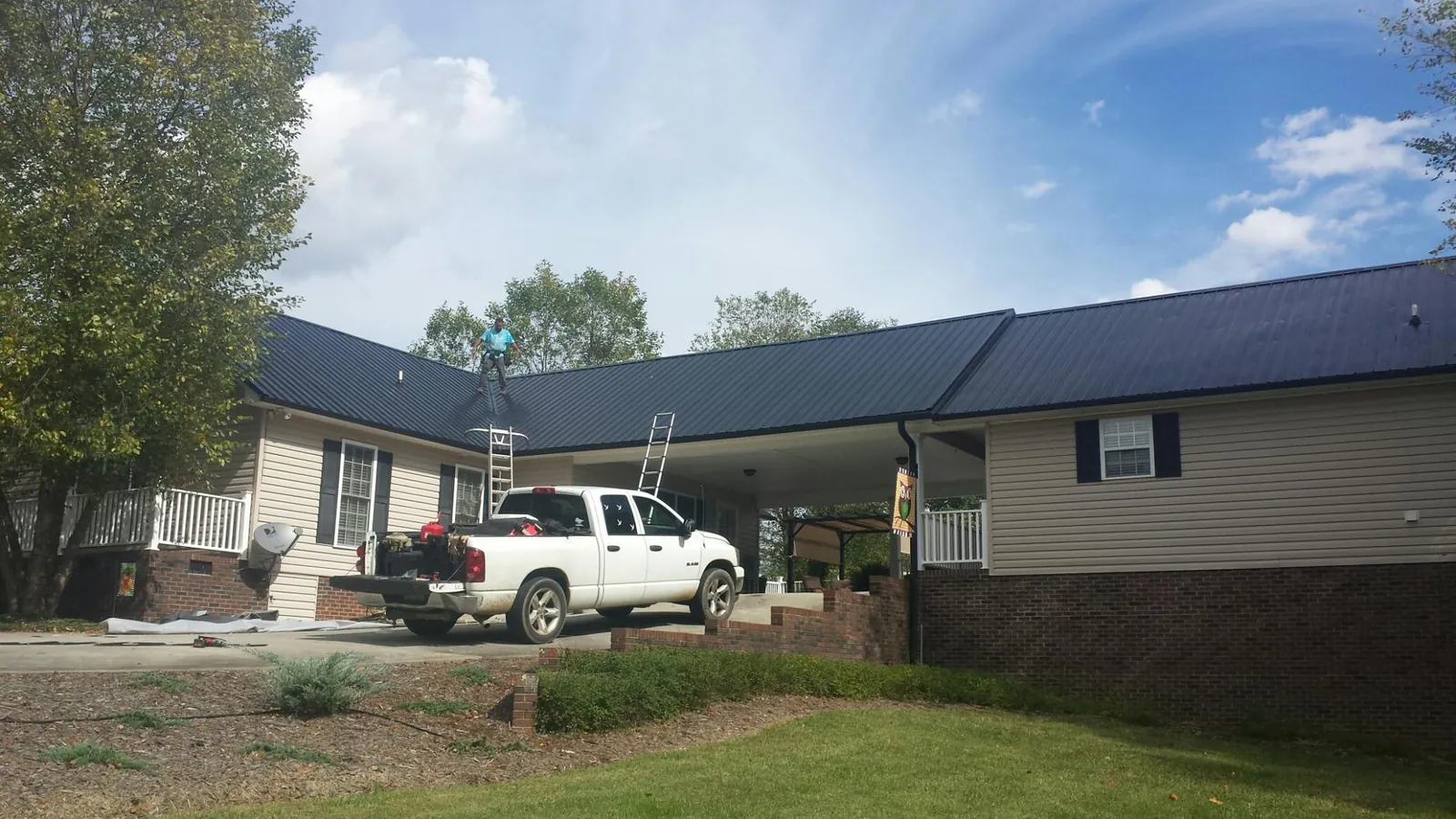 Black metal roof over a home and attached breezeway with ladders set in Dorchester Center