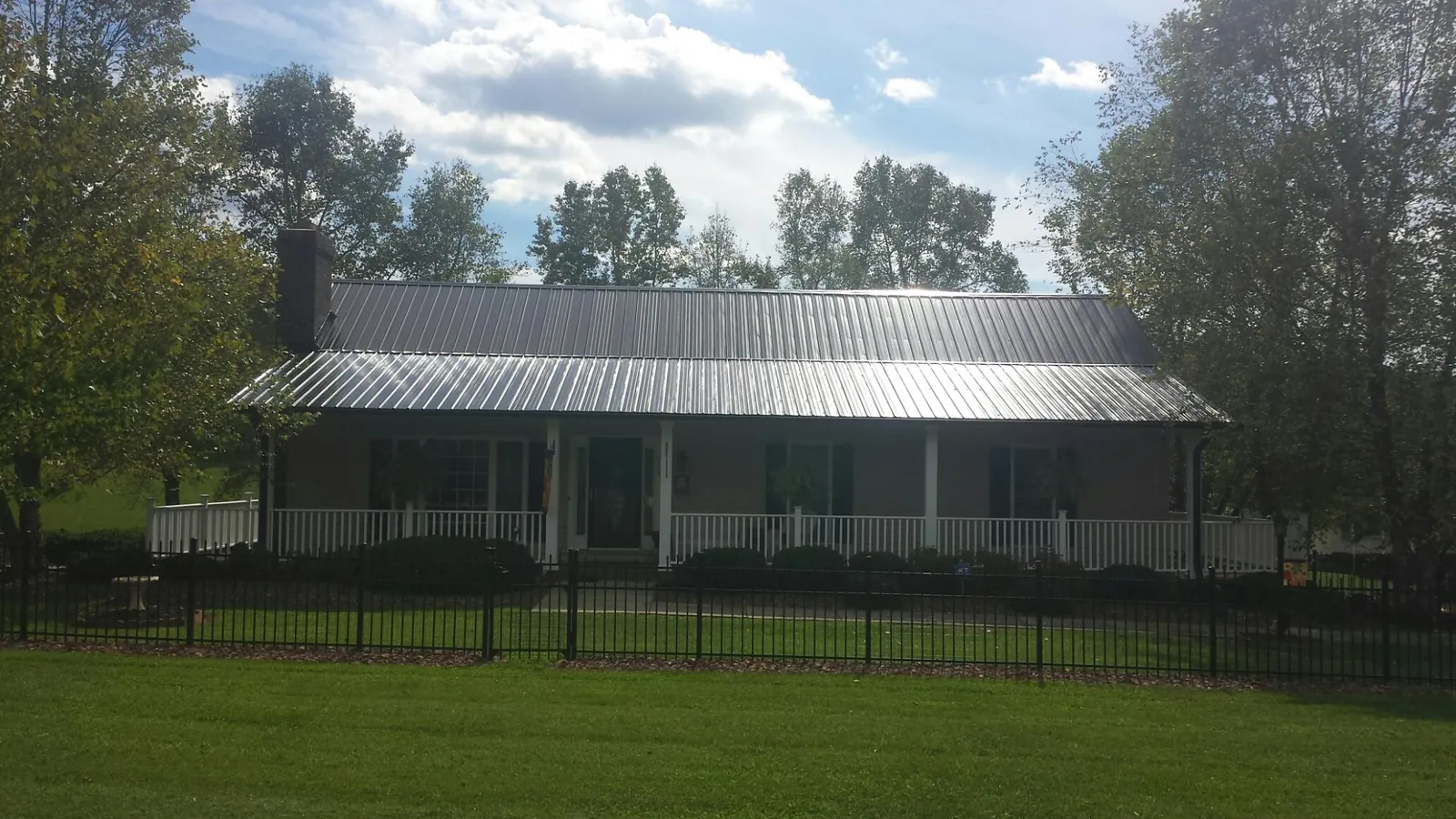 Gray metal roof on a brick ranch with a full width front porch — Gutter Guard Installation work by our crew in Dorchester Center