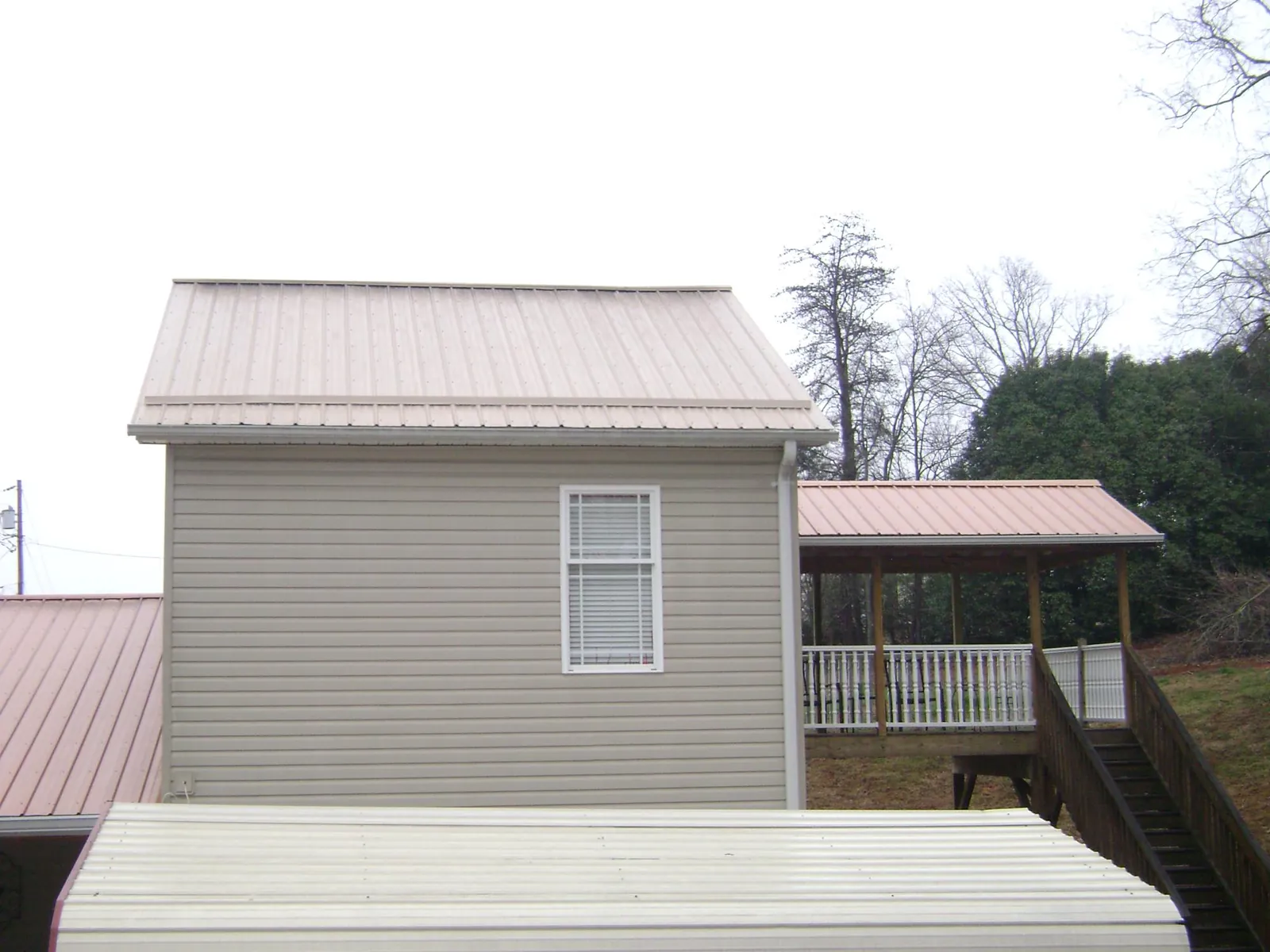 Tan metal roofs on a two story addition and attached porch, from a Roof Replacement job in Dorchester Center
