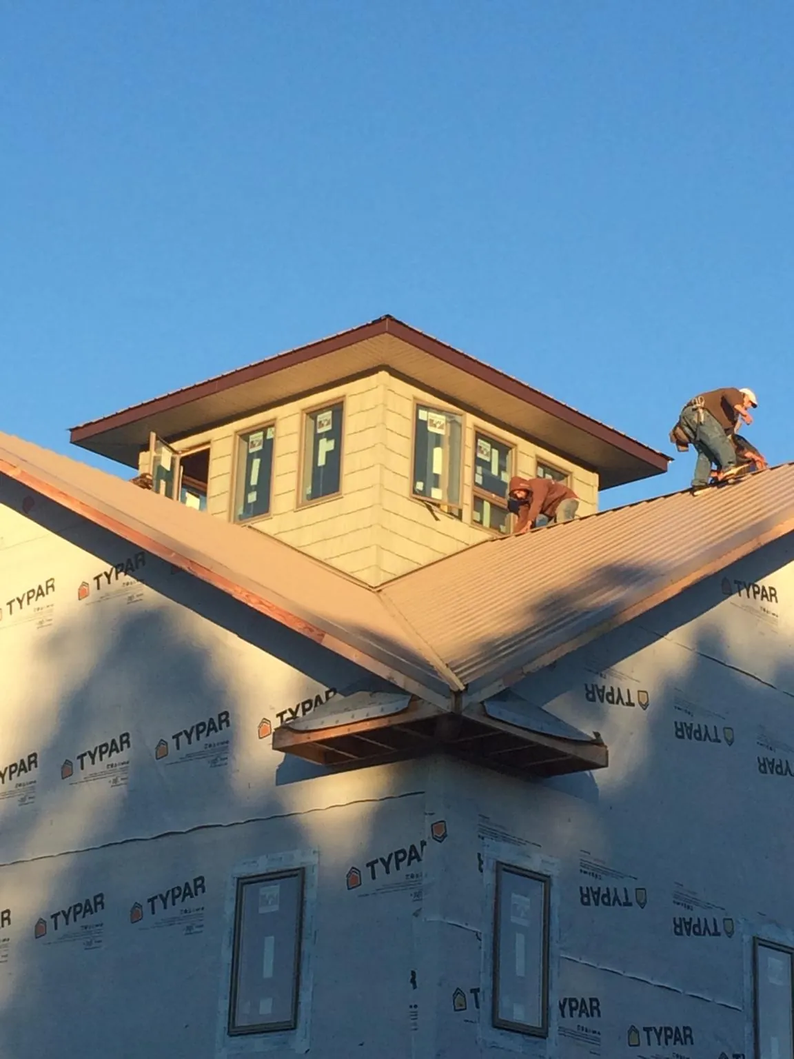 Roofers working around a rooftop cupola on a new metal roof at sunset — Roof Waterproofing in Dorchester Center by Roofing Brothers